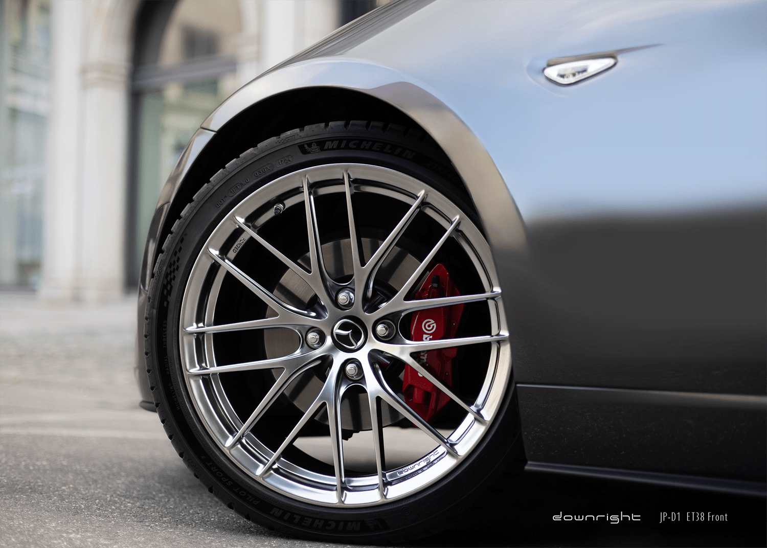 Close-up of a grey Mazda MX-5 ND with a detailed wheel design of downright in Diamond Silver and red Brembo brake caliper on a blurred urban background
