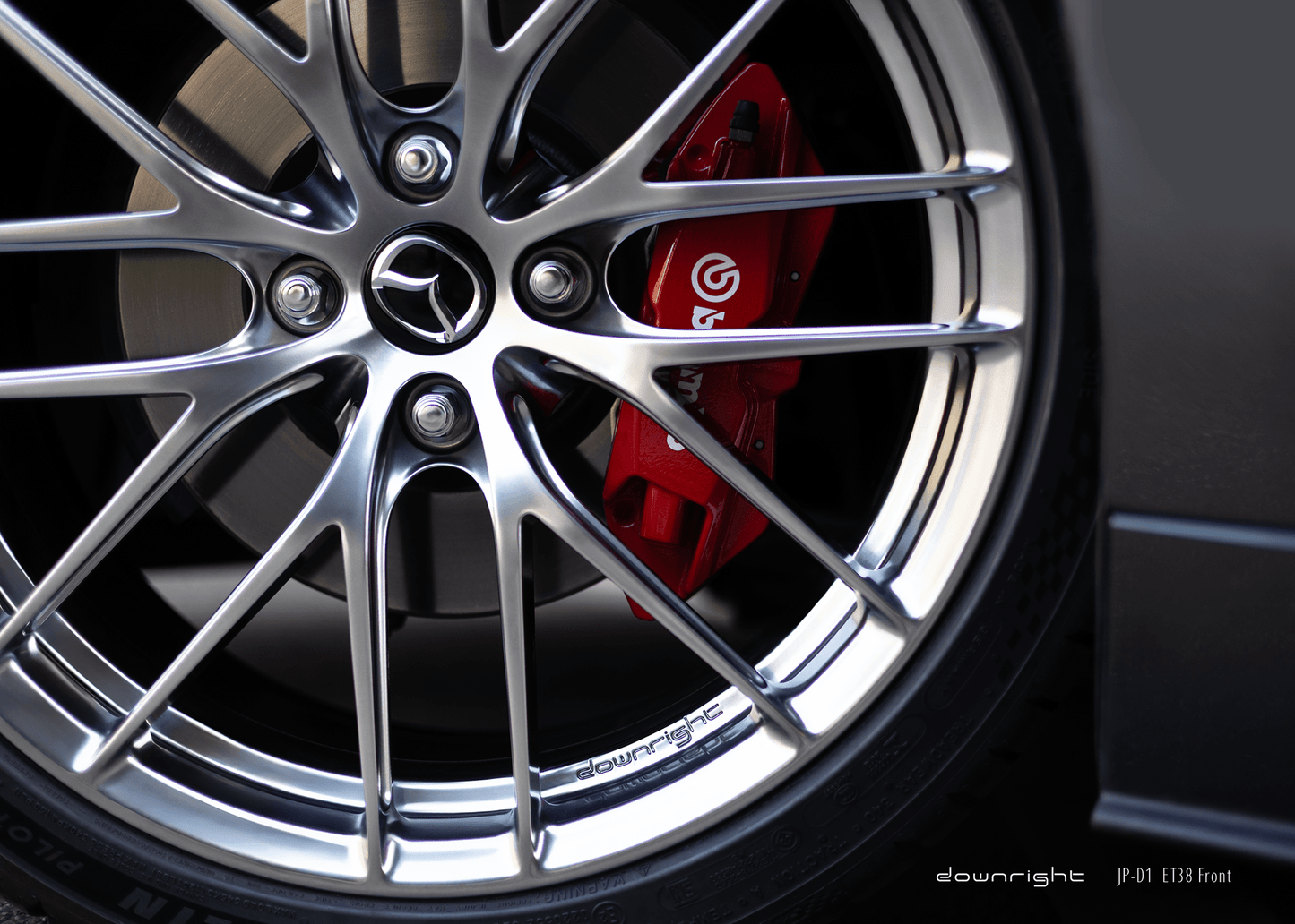 Close-up of a grey Mazda MX-5 ND with a detailed wheel design of downright in Diamond Silver and red Brembo brake caliper on a blurred urban background