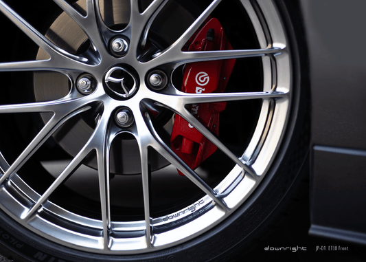 Close-up of a grey Mazda MX-5 ND with a detailed wheel design of downright in Diamond Silver and red Brembo brake caliper on a blurred urban background