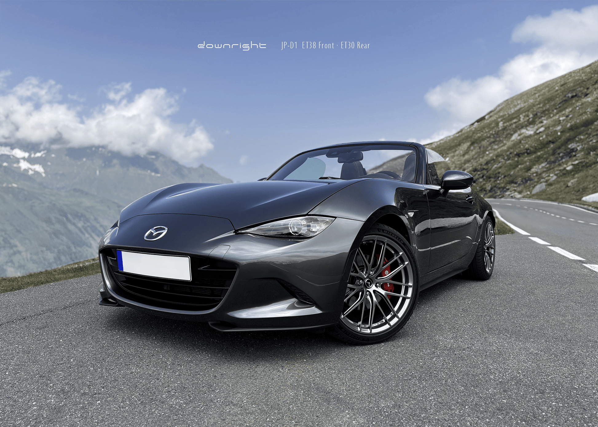 Grey Mazda MX-5 ND with shinny wheels from downright and red Brembo brake caliper parked on a mountain road of Grossglockner with blue sky and clouds